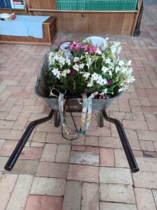 Hanging basket of flowers in a wheel barrow